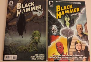 2 Comiccover - auf einem ist eine fliegende schwarze Gruselgestalt abgebildet, auf dem anderen die fünf Helden der Black Hammer-Gruppe