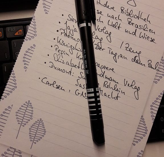 Liste in schwarz geschrieben auf Papier, darauf ein schwarzer Stift