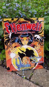 Comic Abenteuer in der Elfenwelt 37 von Bastei vor einer blühen Pflanze, auf dem Cover sind zwei Elfen