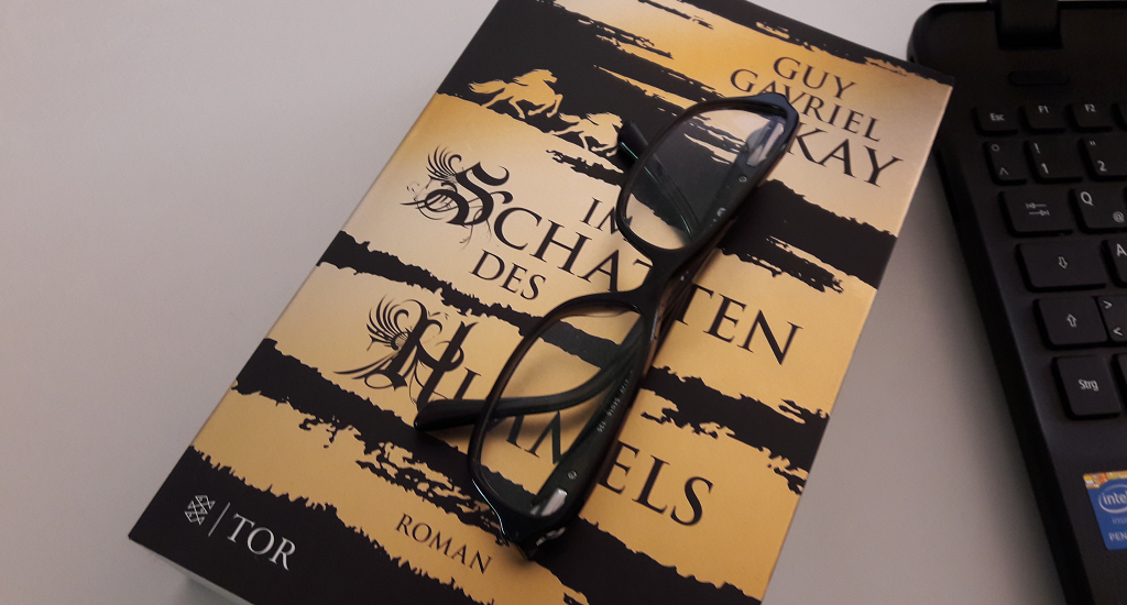 Buch mit goldschwarzem Cover auf dem eine schwarze Brille liegt