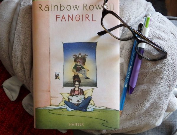Buch liegt auf Plüschkellerassel daneben eine Brille, ein Bleistift, ein Kuli.