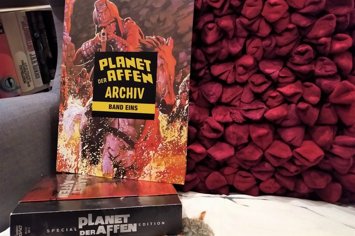 Planet der Affen Archiv 1 Titelbild zeigt den Comic auf einem Sessel vor einem roten Kissen und auf der Planet der Affen-DVD-Box