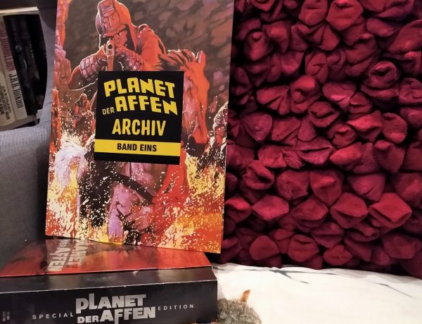 Planet der Affen Archiv 1 Titelbild zeigt den Comic auf einem Sessel vor einem roten Kissen und auf der Planet der Affen-DVD-Box