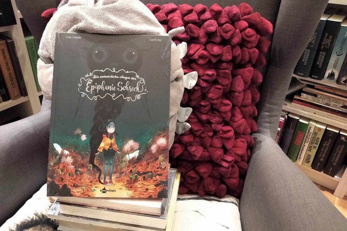 Epiphanie - Comic steht auf einem Bücherstapel auf einem Sessel