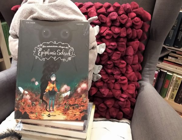 Epiphanie - Comic steht auf einem Bücherstapel auf einem Sessel