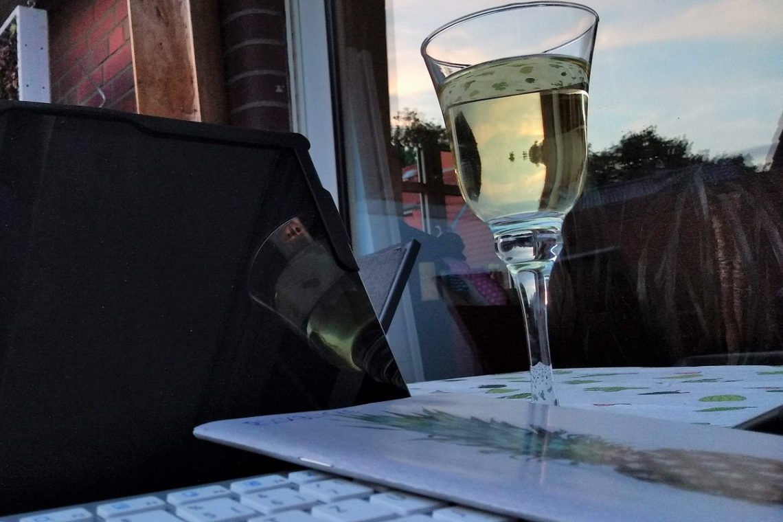 Notebook und ein Glas Weißwein