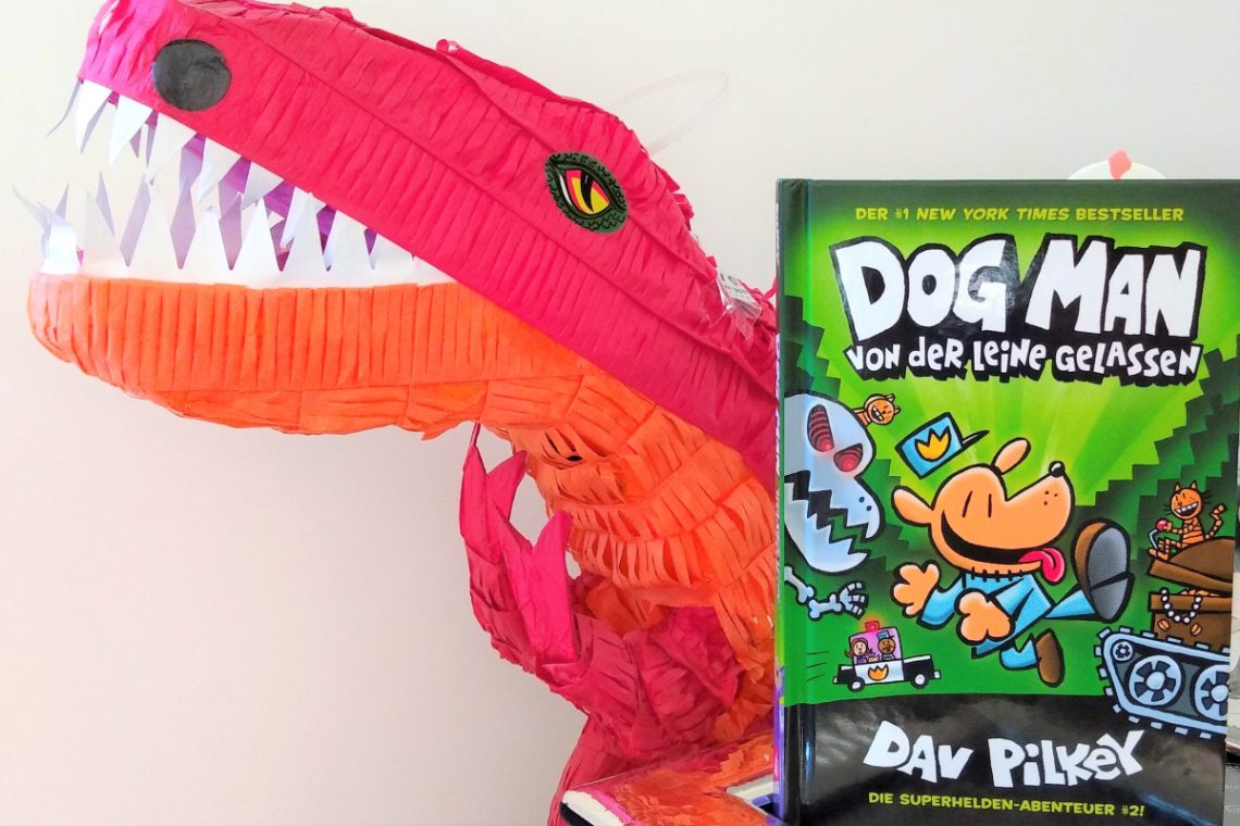 Dog Man Comic neben einem großen roten T-Rex aus Papier