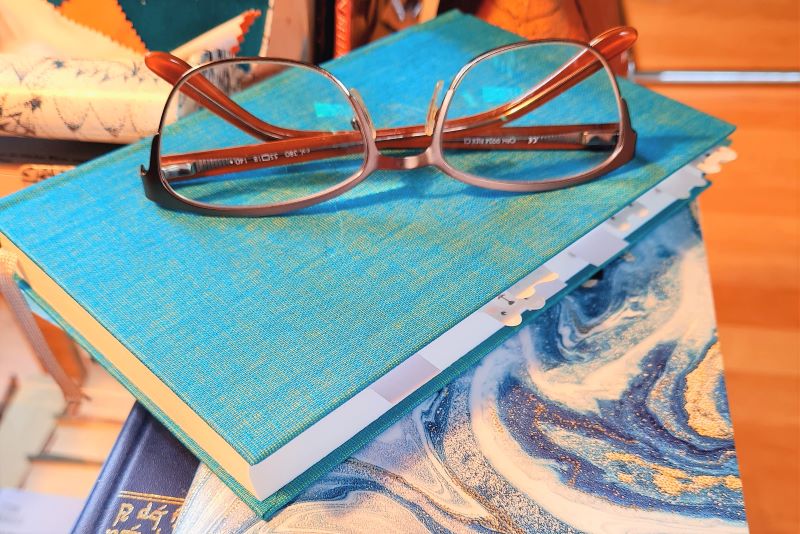 Brille liegt auf einem kleinen Stapel Bücher