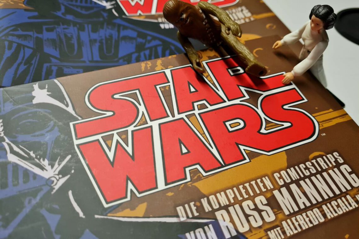 Buch Star Wars - Die kompletten Comicstrips Band 1 ist zu sehen, daneben zwei klassisches Star Wars Actionfiguren von Leia und Chewbacca