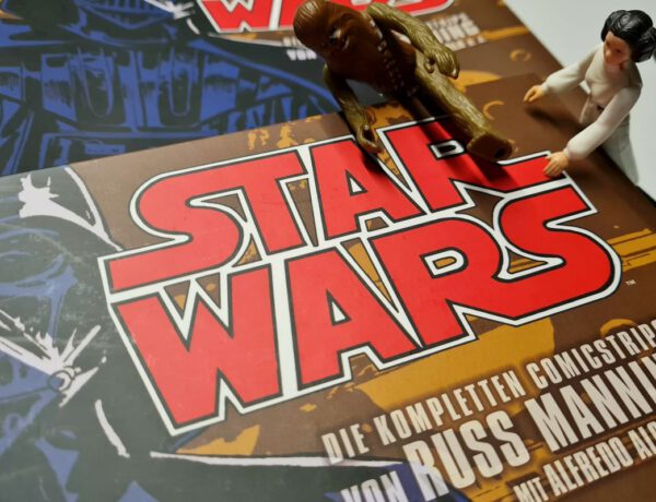 Buch Star Wars - Die kompletten Comicstrips Band 1 ist zu sehen, daneben zwei klassisches Star Wars Actionfiguren von Leia und Chewbacca