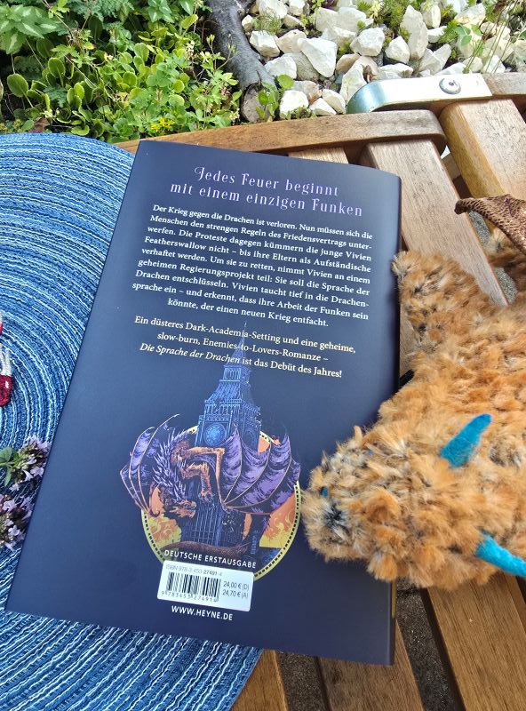 Buch liegt auf einem Tisch im Garten, man sieht die Rückseite