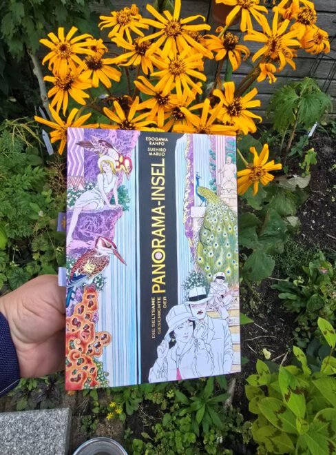 Manga vor einer gelb blühenden Blume