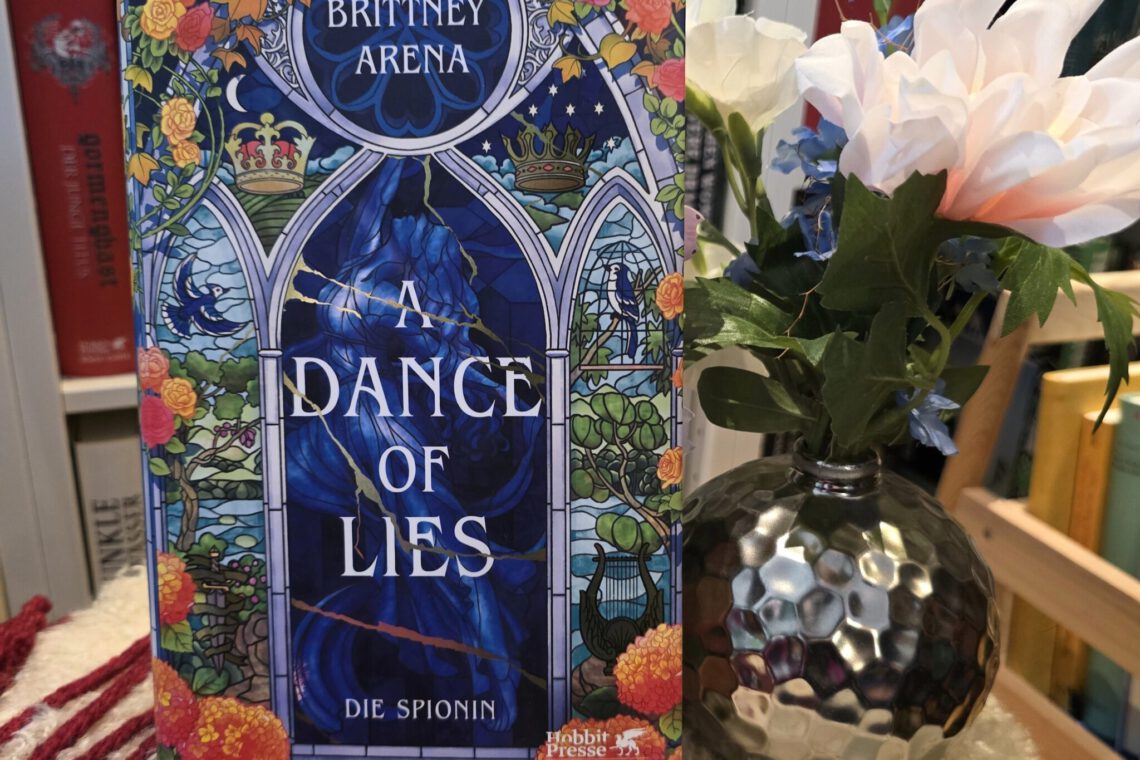 Buch steht vor einem Regal, daneben eine silberne runde Vase mit Blumen