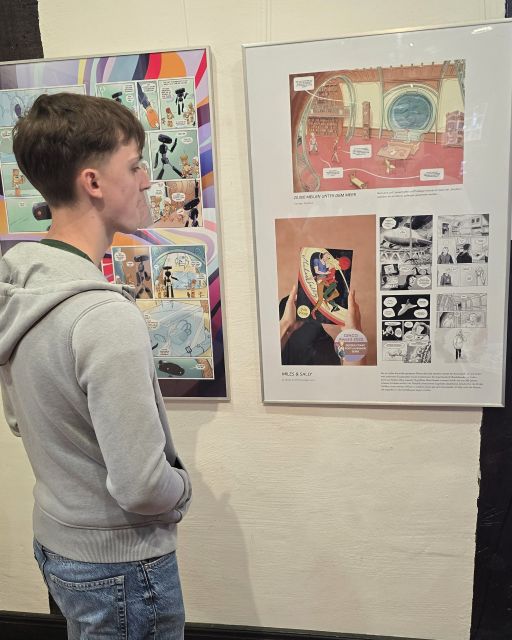 Ein junger Mensch schaut Comics an, die ausgestellt sind